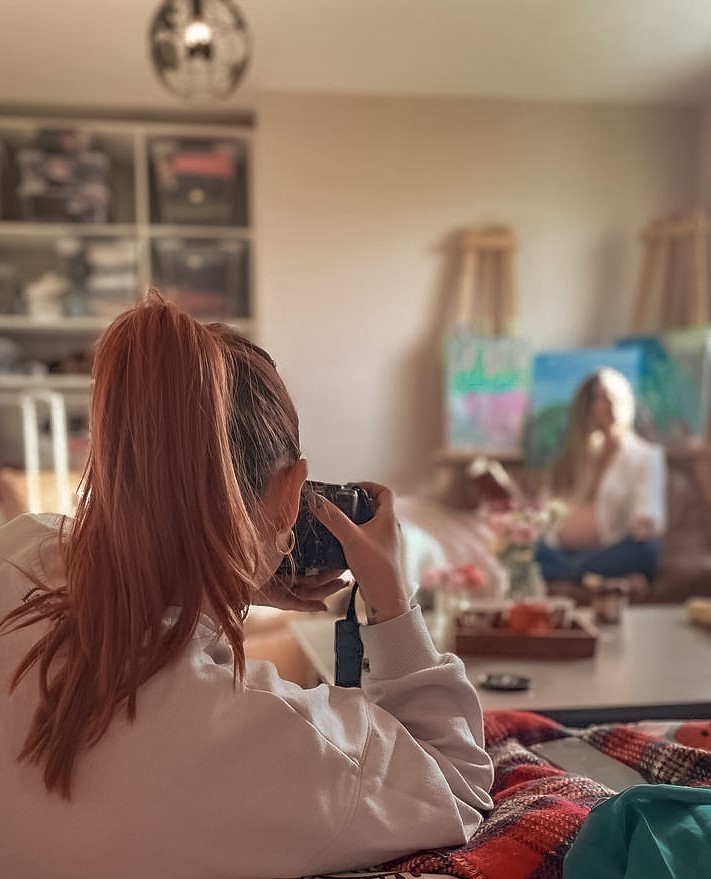 Lucie Brisseau, photographe professionnelle des instantanés de Lucie, vue de dos et en train de photographier une jeune femme.