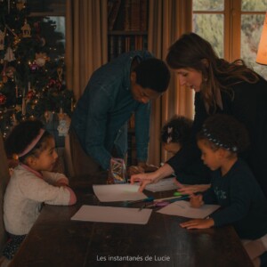 Séance photo en famille de deux parents et leurs trois enfants en train de colorier.